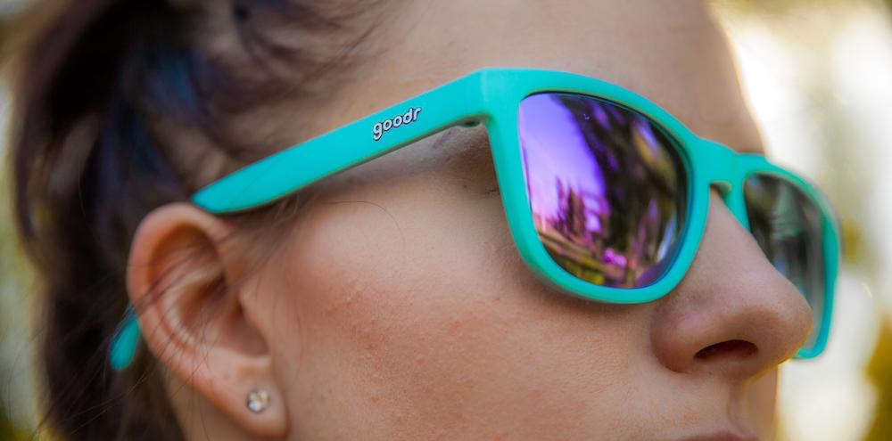 Goodr Electric Dinotopia Carnival OG running sunglasses with vibrant pink and purple frame, polarized UV400 lenses, and no-slip, no-bounce design — ideal for running and active lifestyles.
