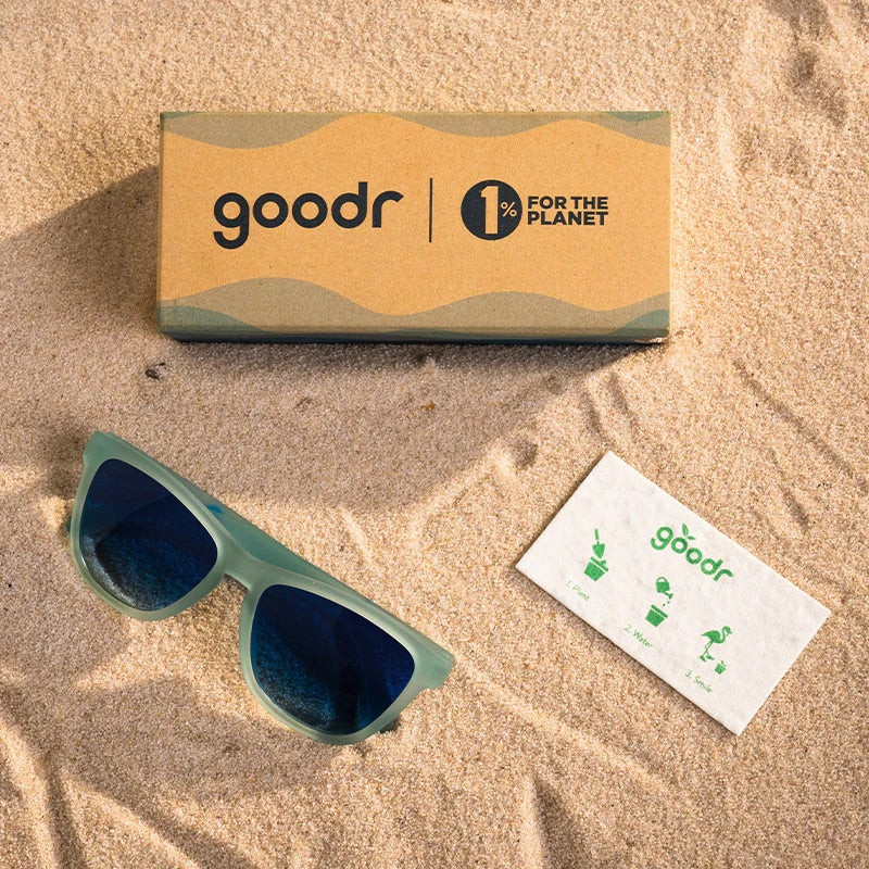 “goodr These Shades Are Still Trash sunglasses with frosted translucent frame and blue mirrored lenses made from recycled materials.”